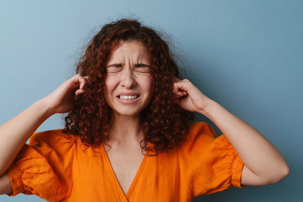 unhappy ginger woman grimacing and plugging her ea 2023 11 27 05 29 05 utc